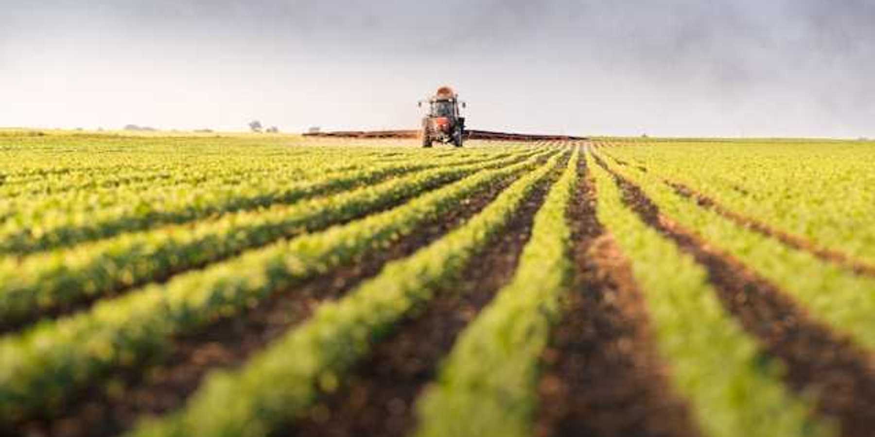 A farm field with a tractor in the background