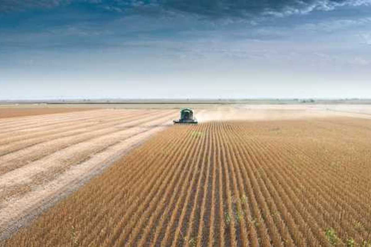 A farm tractor driving across a dry field