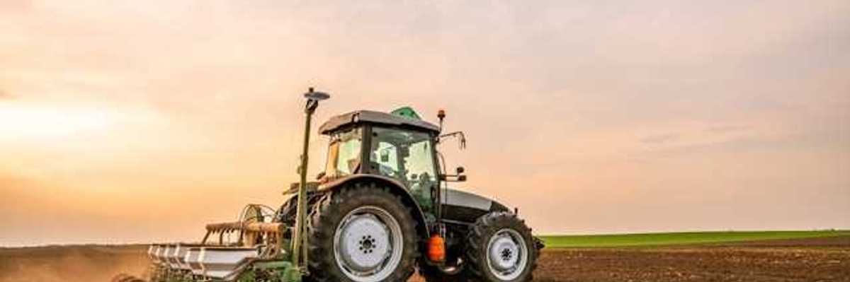 A farm tractor driving across a field of soil