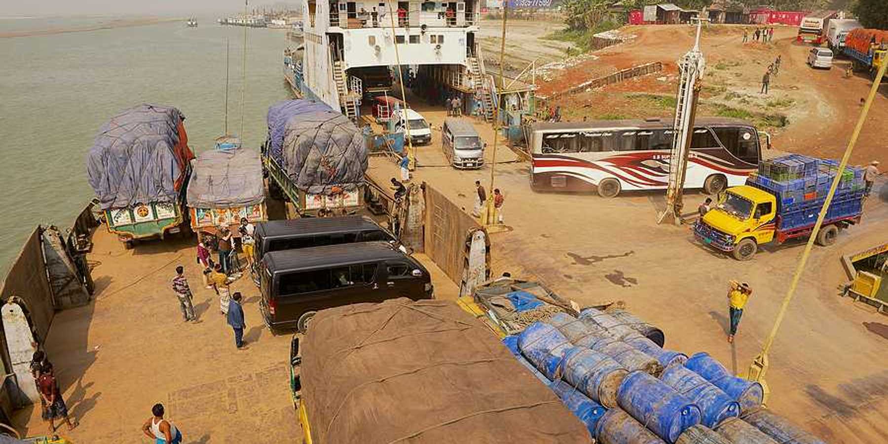 A ferry unloading trucks on the edge of a river in Bangladesh