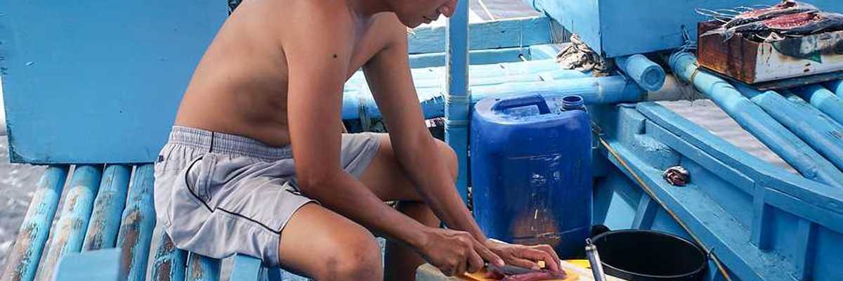 A filipino fisherman filleting a fish on his boat