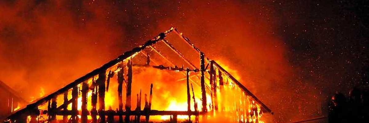 A fireman directs a water stream at a burning house