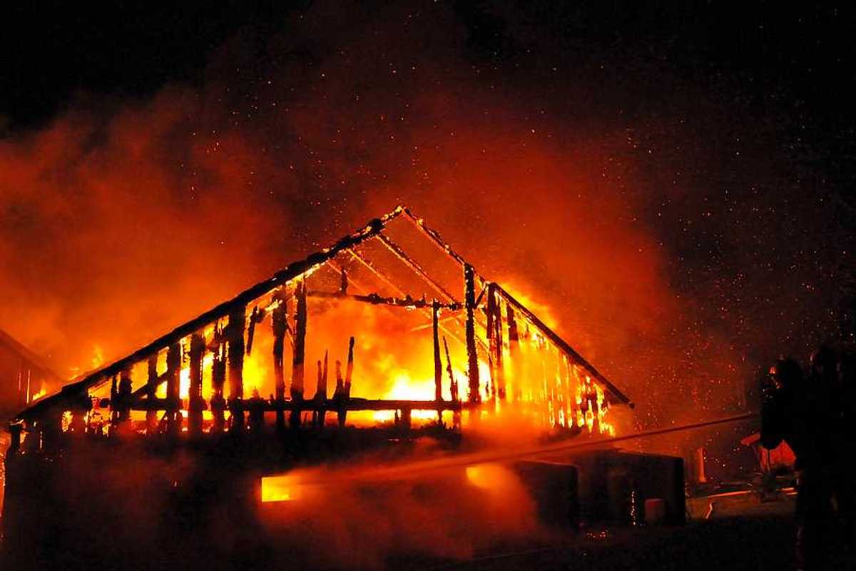 A fireman directs a water stream at a burning house