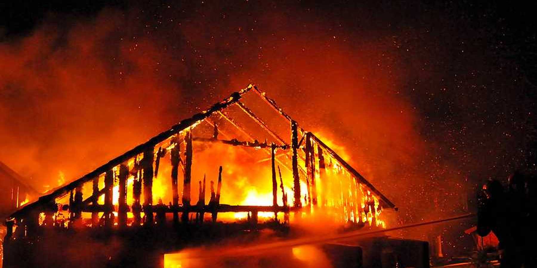 A fireman directs a water stream at a burning house