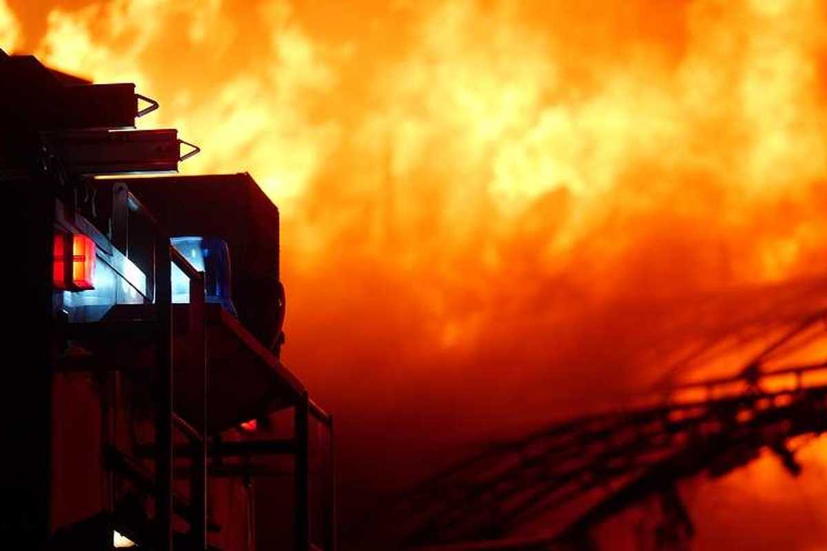 A firetruck pulling up to a house on fire