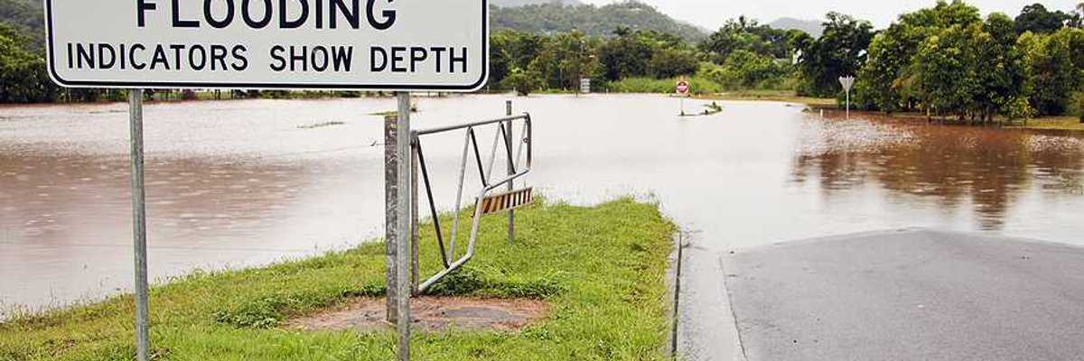A flooded road with a sign indicating that the road is subject to flooding