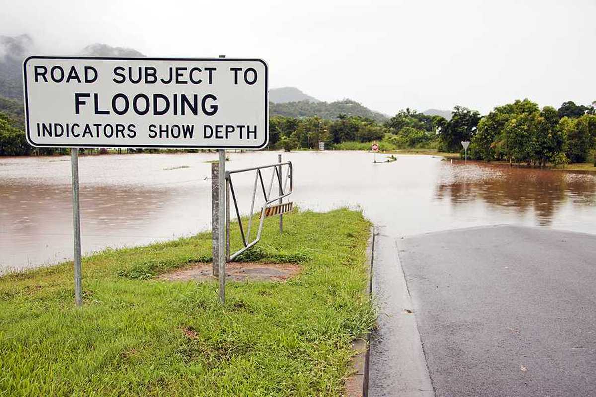 A flooded road with a sign indicating that the road is subject to flooding