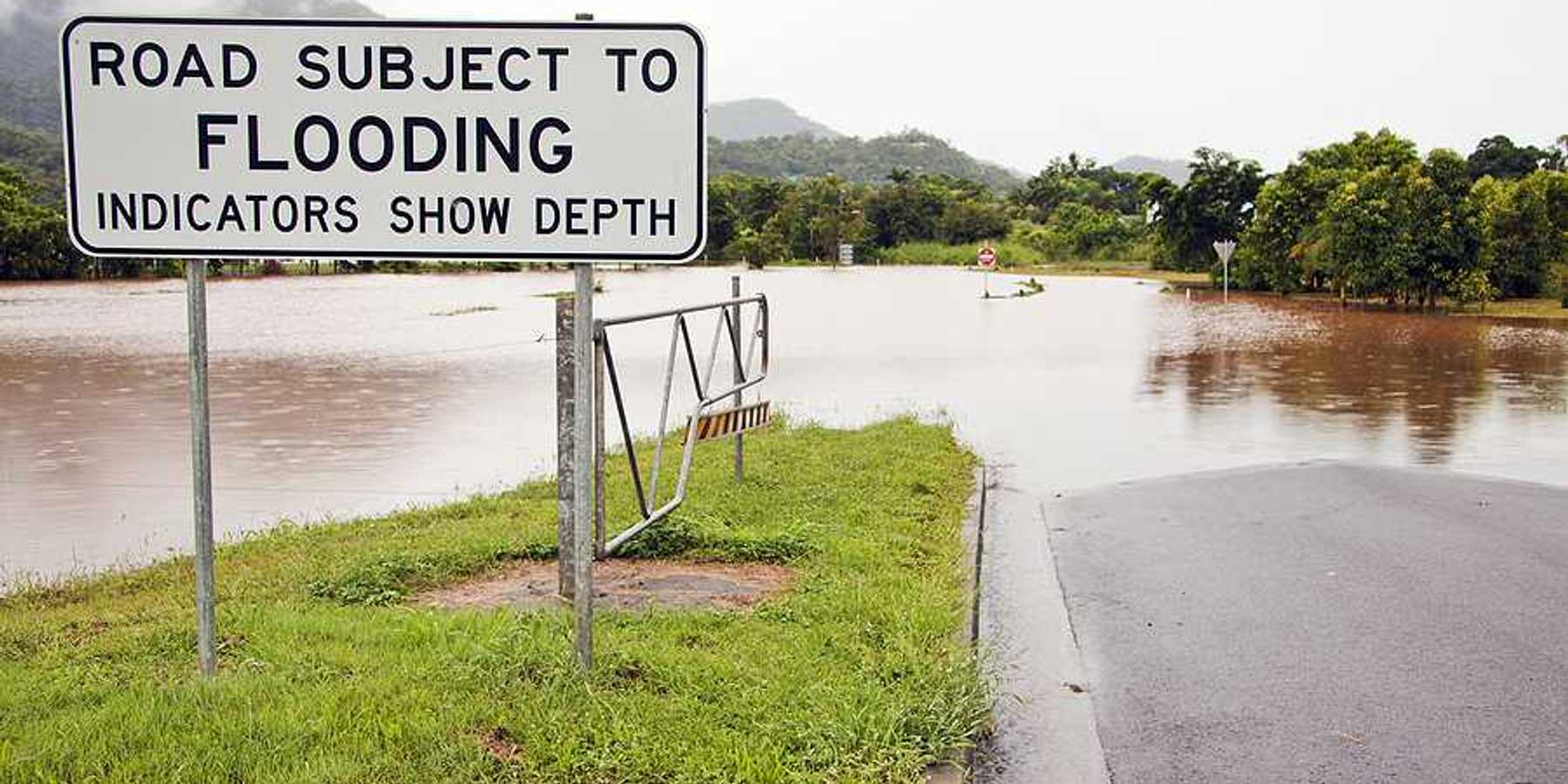 A flooded road with a sign indicating that the road is subject to flooding
