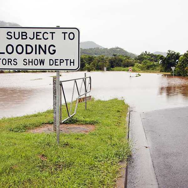 A flooded road with a sign indicating that the road is subject to flooding