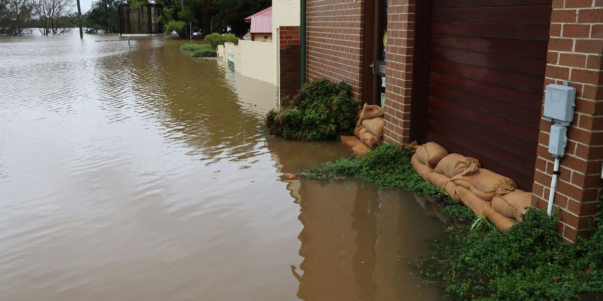 A flooded street with a building and sandbags protecting the doors.