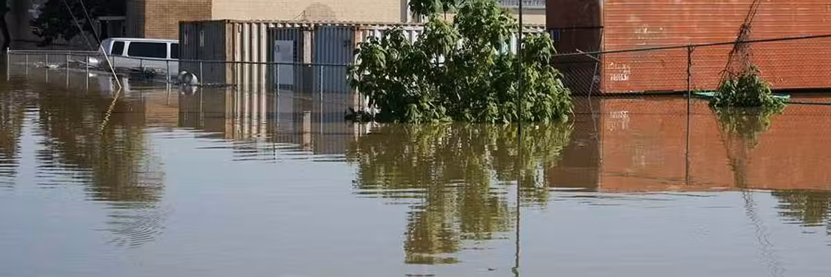 A flooded street with building and a van submerged