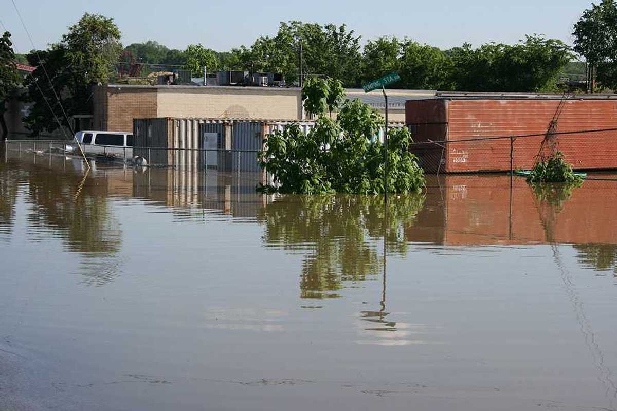 A flooded street with building and a van submerged