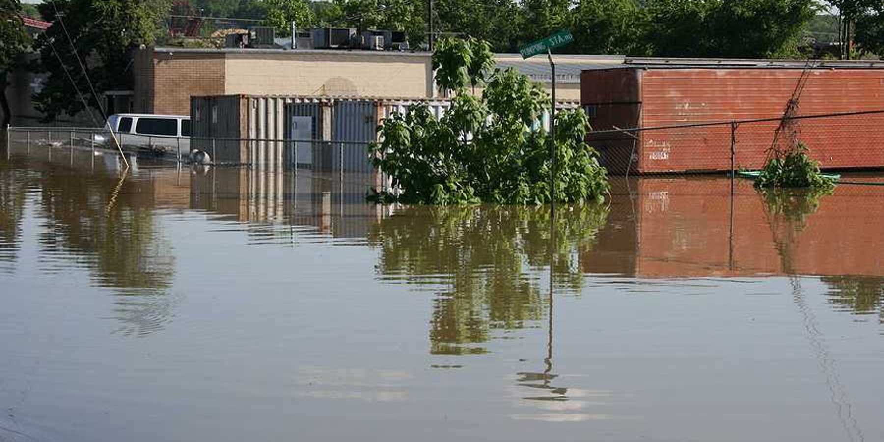A flooded street with building and a van submerged