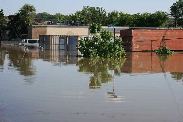 A flooded street with building and a van submerged