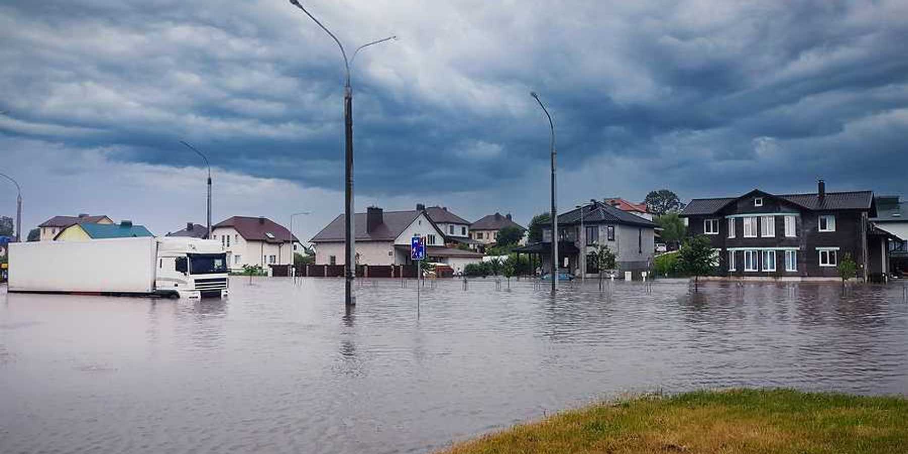 A flooded street with houses in the background
