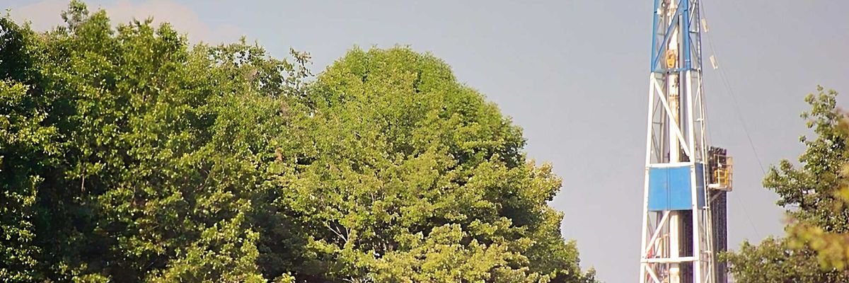 A fracking rig above a group of trees.