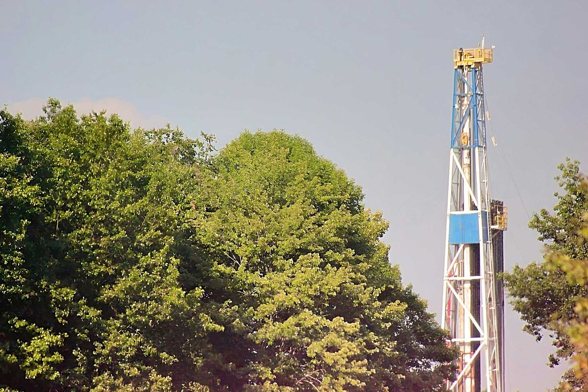 A fracking rig above a group of trees.