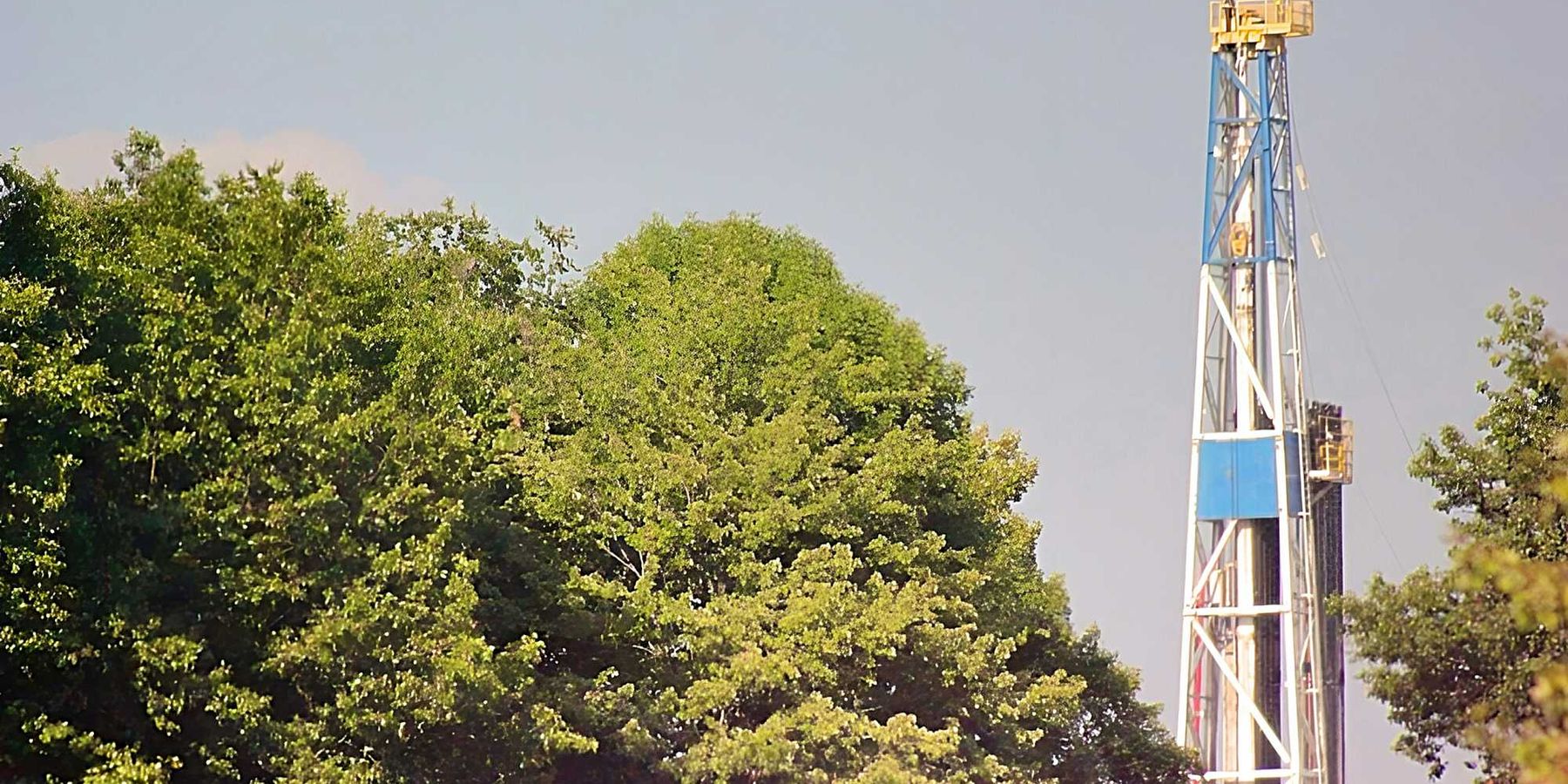 A fracking rig above a group of trees.