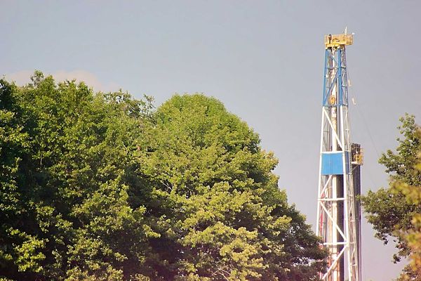 A fracking rig above a group of trees.