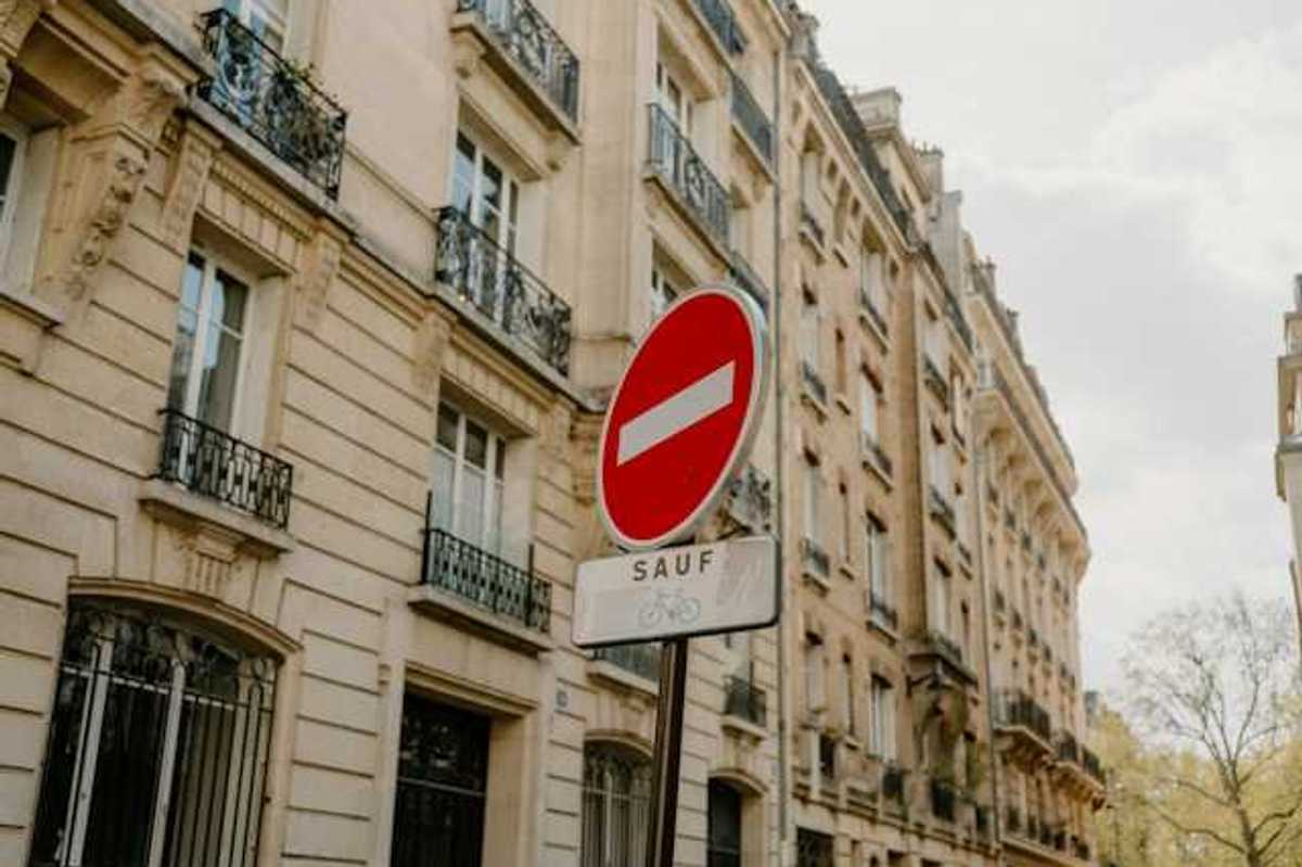 A French sign restricting cars from a street with Parisian buildings in the background