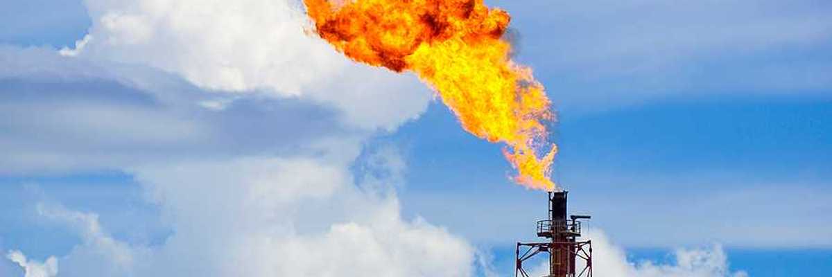 A gas tower flaring orange flames into the sky