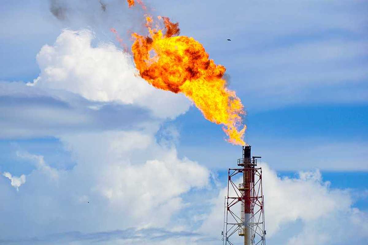 A gas tower flaring orange flames into the sky