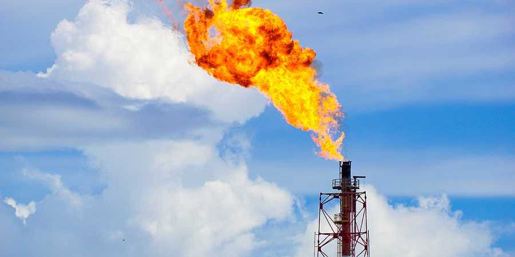 A gas tower flaring orange flames into the sky
