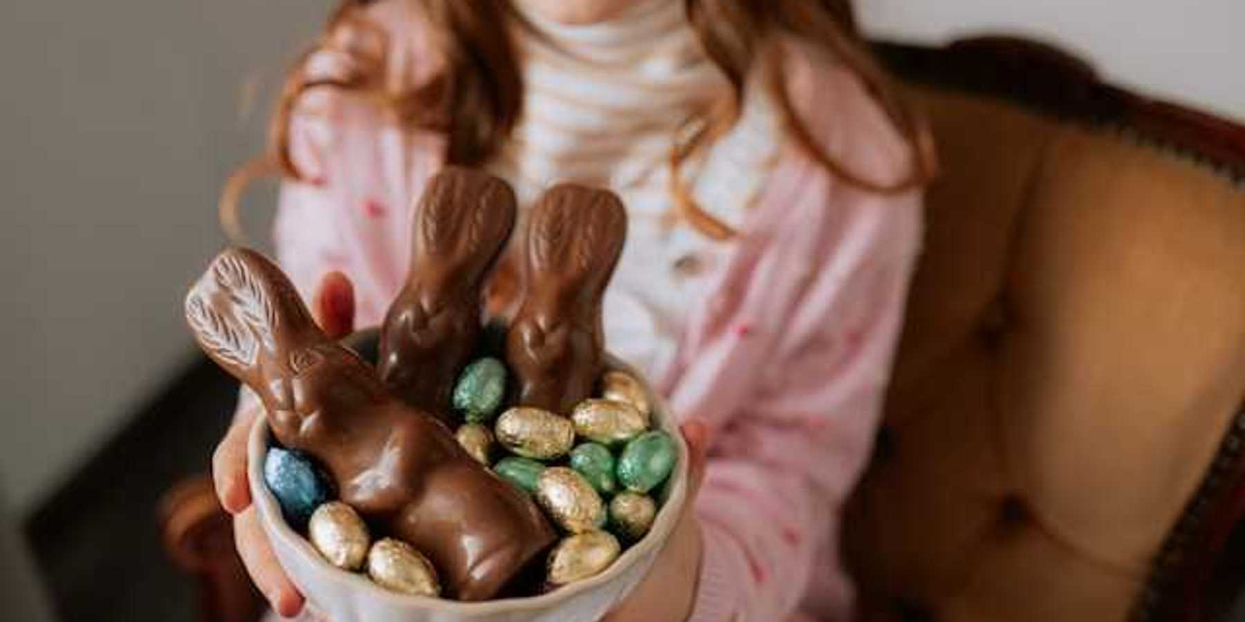 A girl holding a bowl with easter chocolate in it