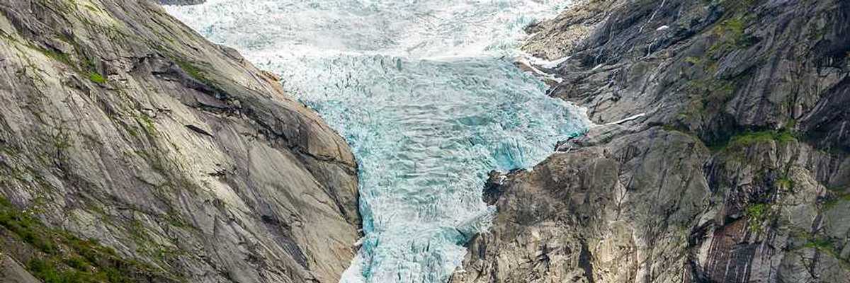 A glacier flowing down between two dry rocky ridges