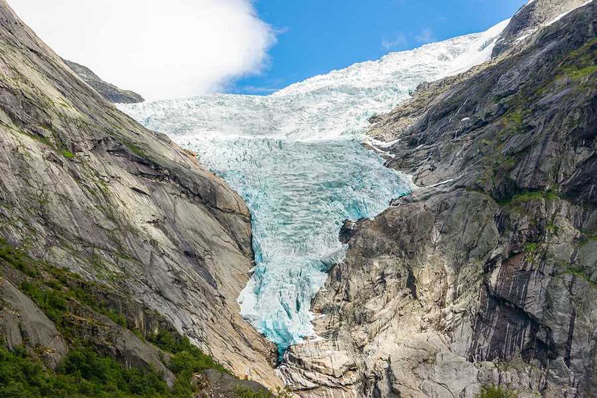 A glacier flowing down between two dry rocky ridges