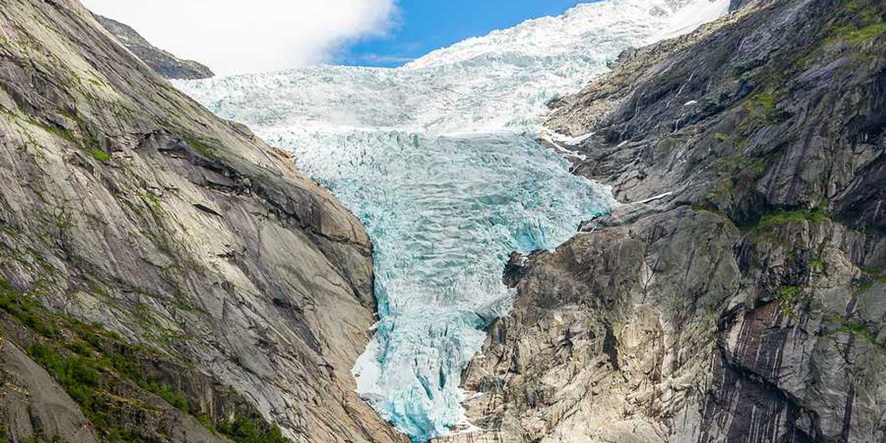 A glacier flowing down between two dry rocky ridges