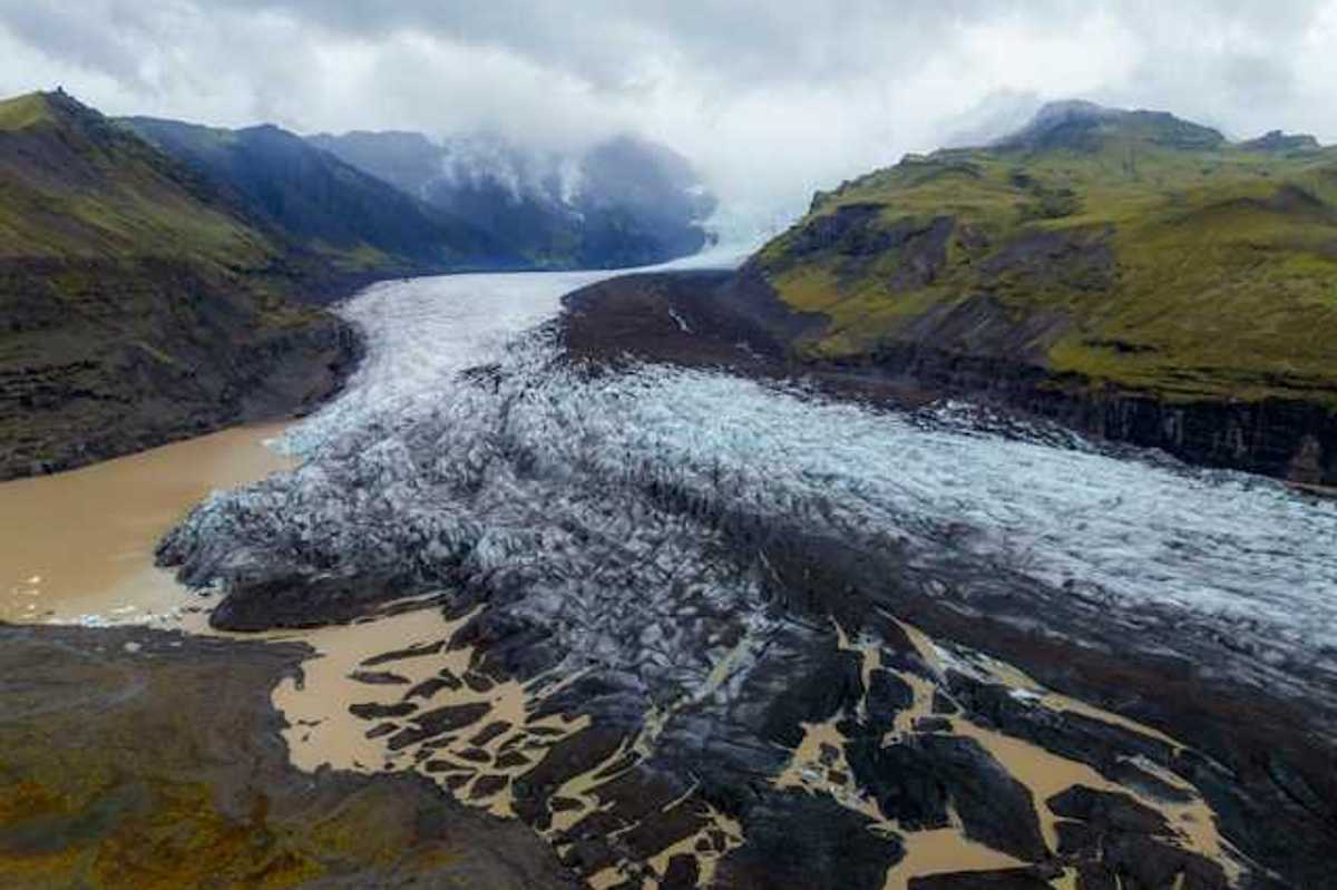 A glacier shown between two low mountain ranges