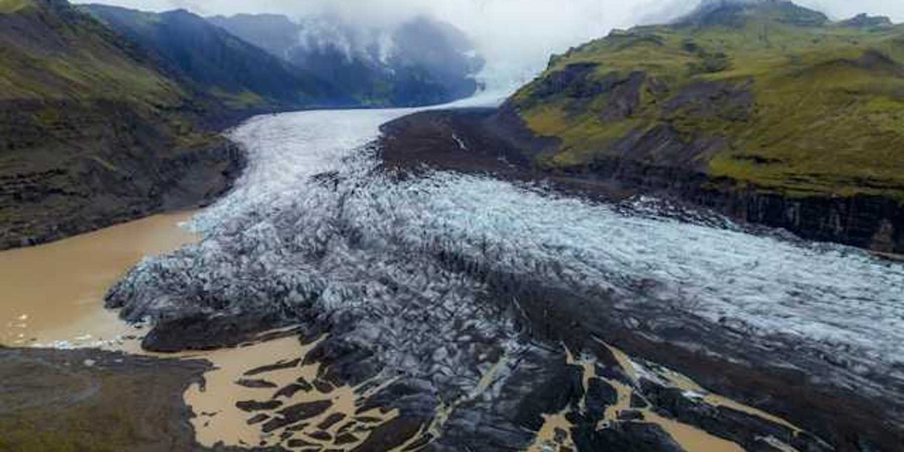 A glacier shown between two low mountain ranges