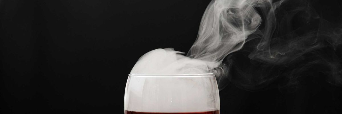 a glass of wine with smoke coming out of it