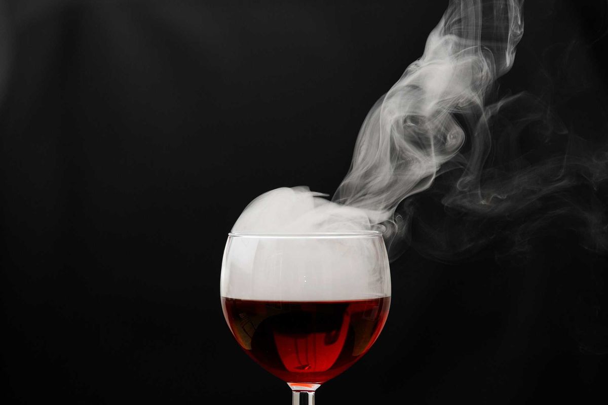 a glass of wine with smoke coming out of it