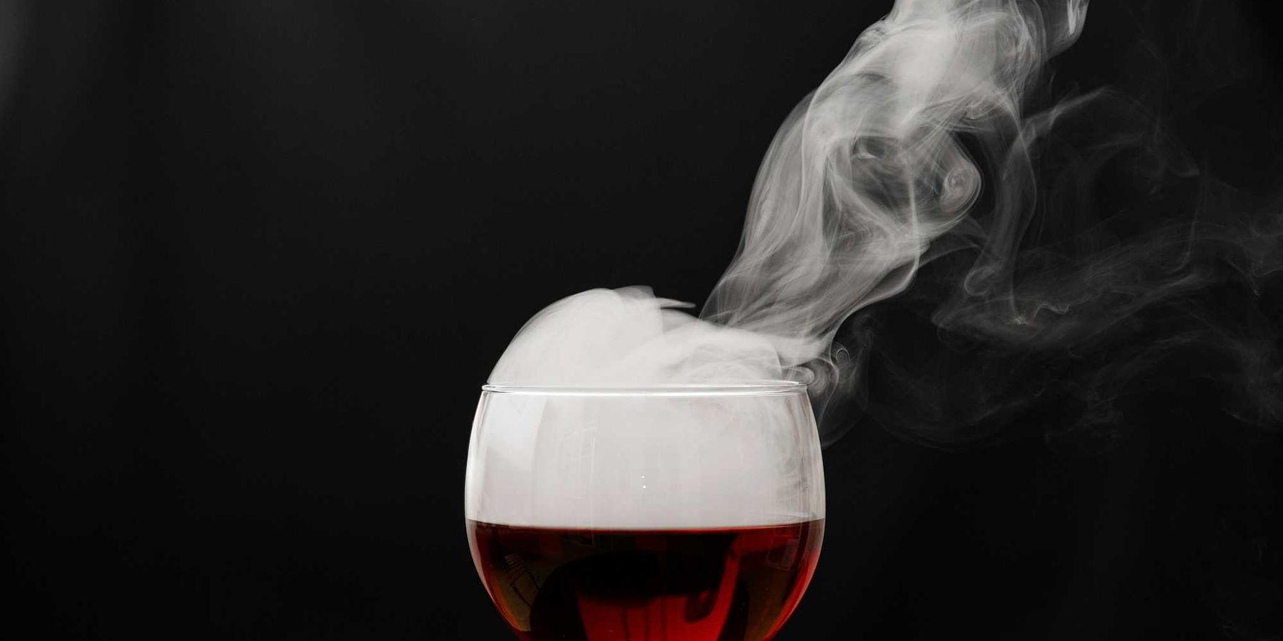 a glass of wine with smoke coming out of it