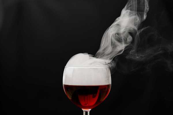 a glass of wine with smoke coming out of it