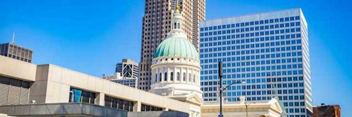 A government building in a downtown area with a tall building in the background