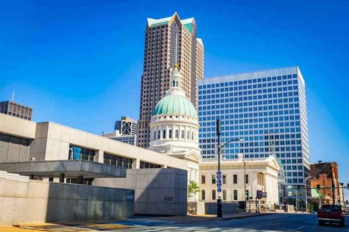 A government building in a downtown area with a tall building in the background