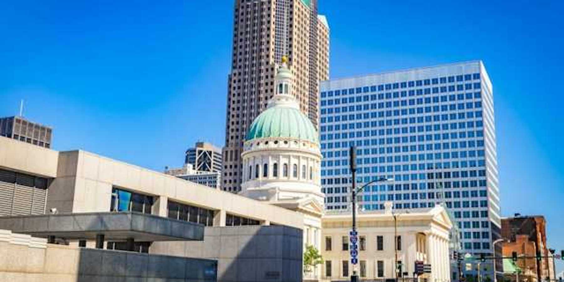 A government building in a downtown area with a tall building in the background