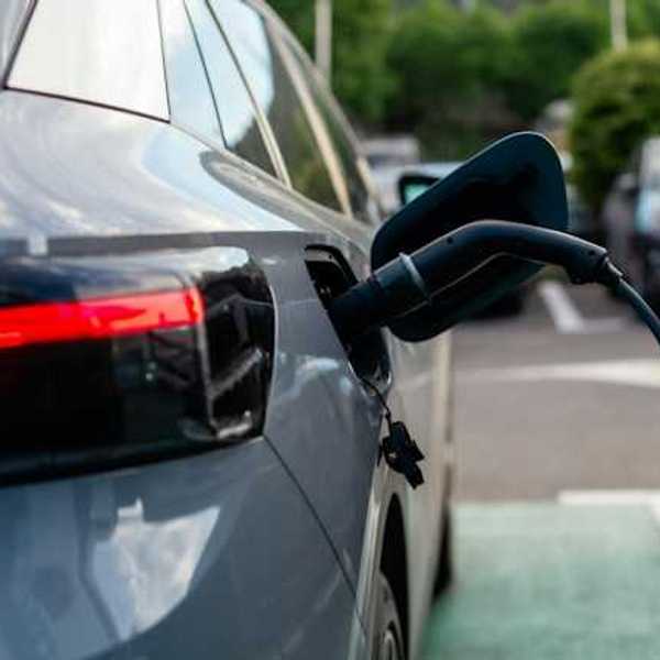 A gray sedan being charged at an electric charging station
