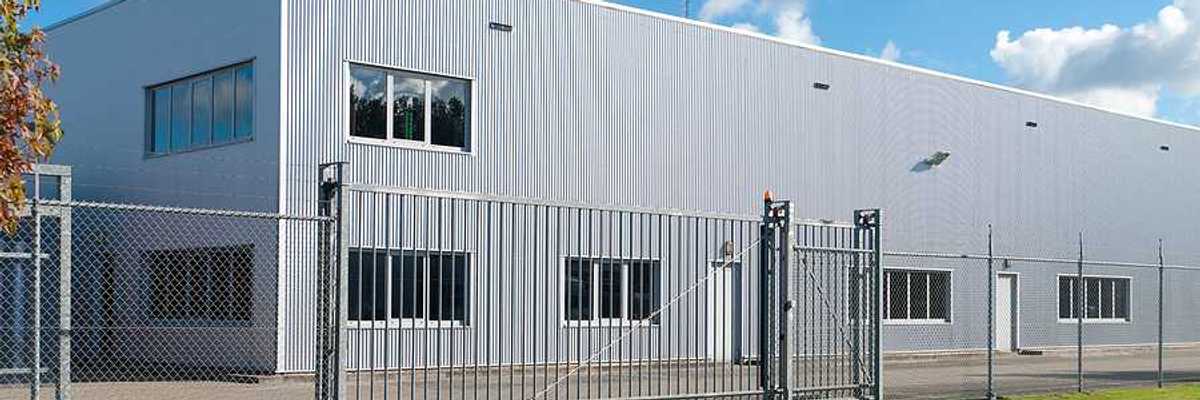 A grey metal industrial building surrounded by fencing