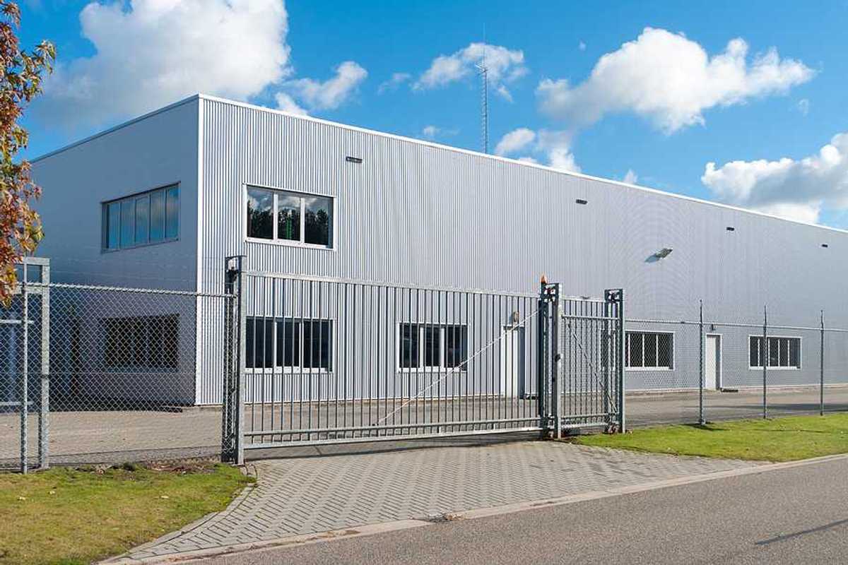 A grey metal industrial building surrounded by fencing