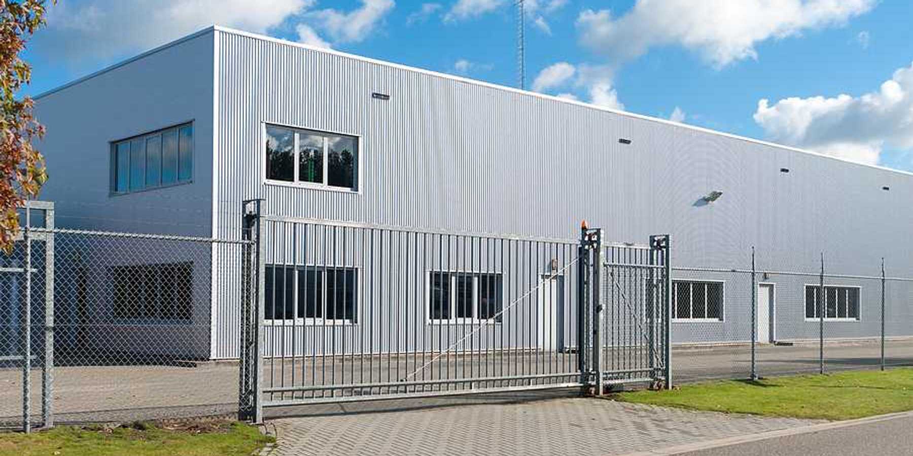 A grey metal industrial building surrounded by fencing