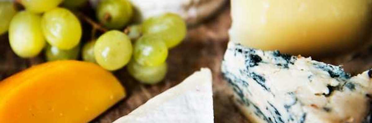 A group of cheese and grapes on a wooden board