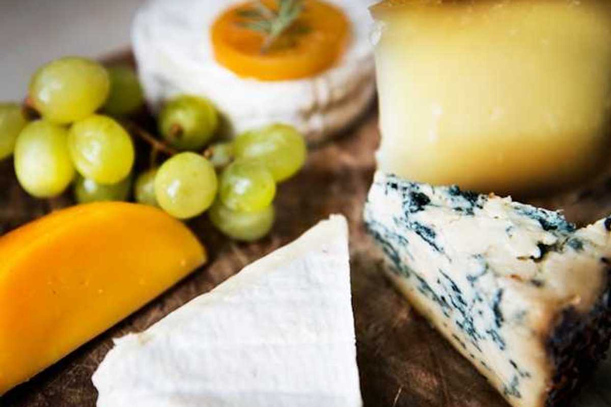 A group of cheese and grapes on a wooden board
