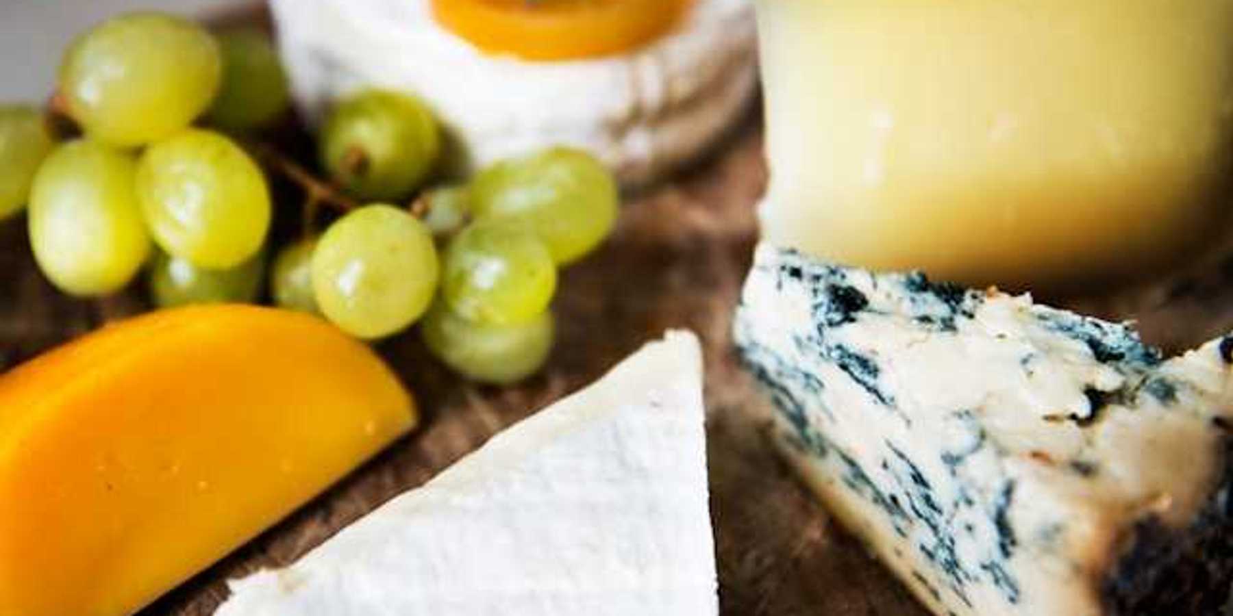 A group of cheese and grapes on a wooden board