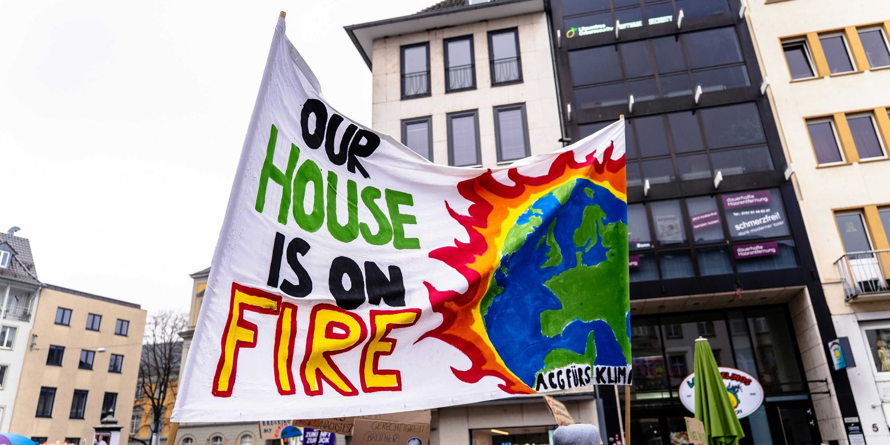 A group of climate protesters holding a sign that says our house is on fire.