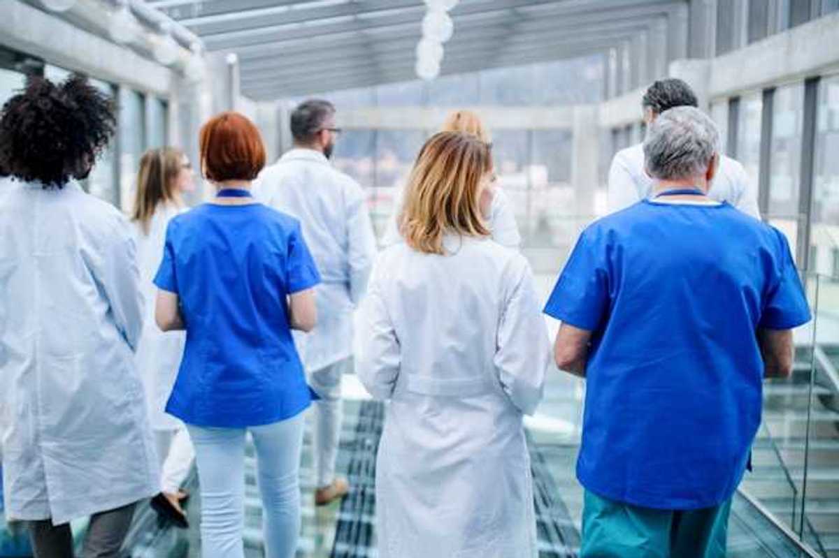 A group of doctors walking down a hallway in a hospital