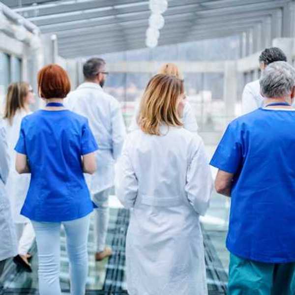 A group of doctors walking down a hallway in a hospital